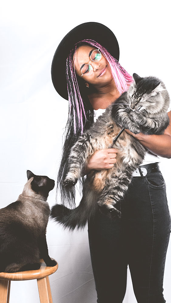 Meagan Bolds self-portrait holding one cat while another looks on