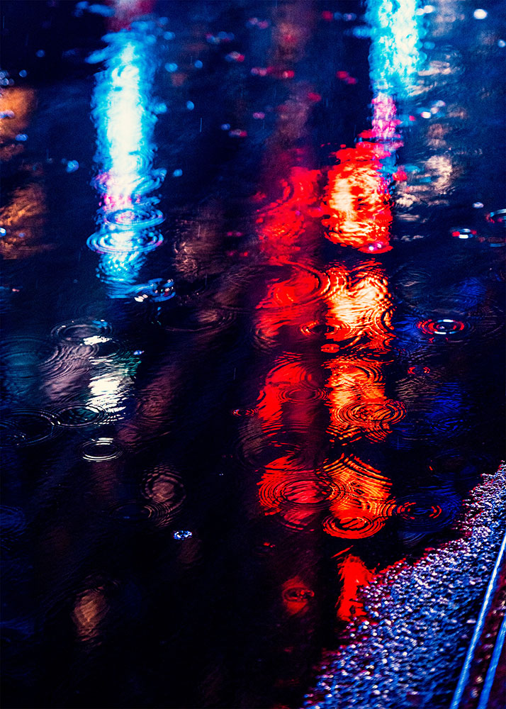 JT photo of the reflection of lights in a puddle on a wet street