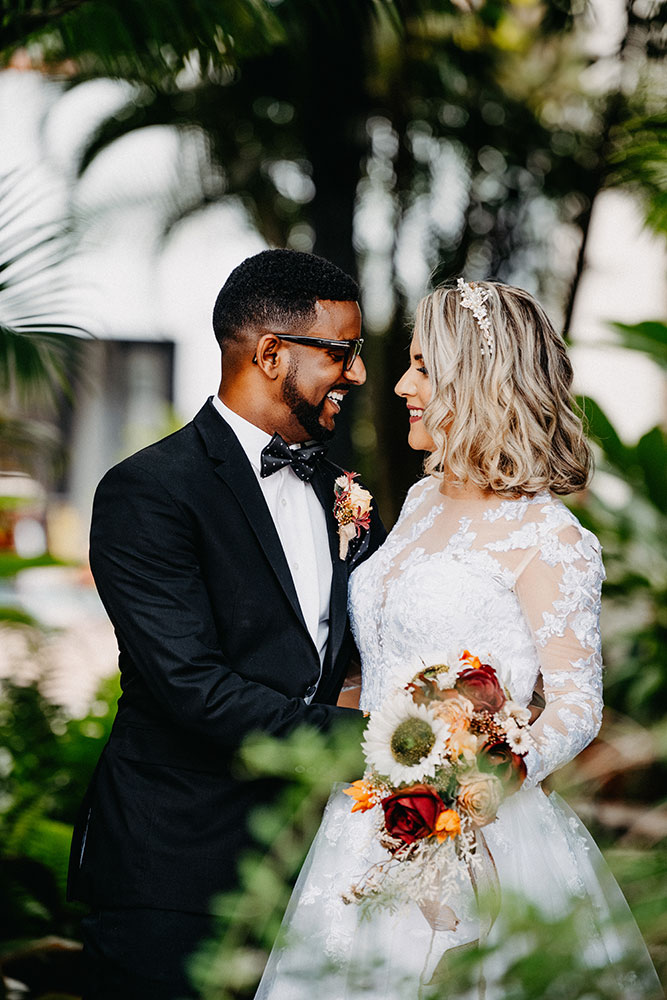 Robert Vasquez photo of a bride and groom smiling at each other surrounded by greenery