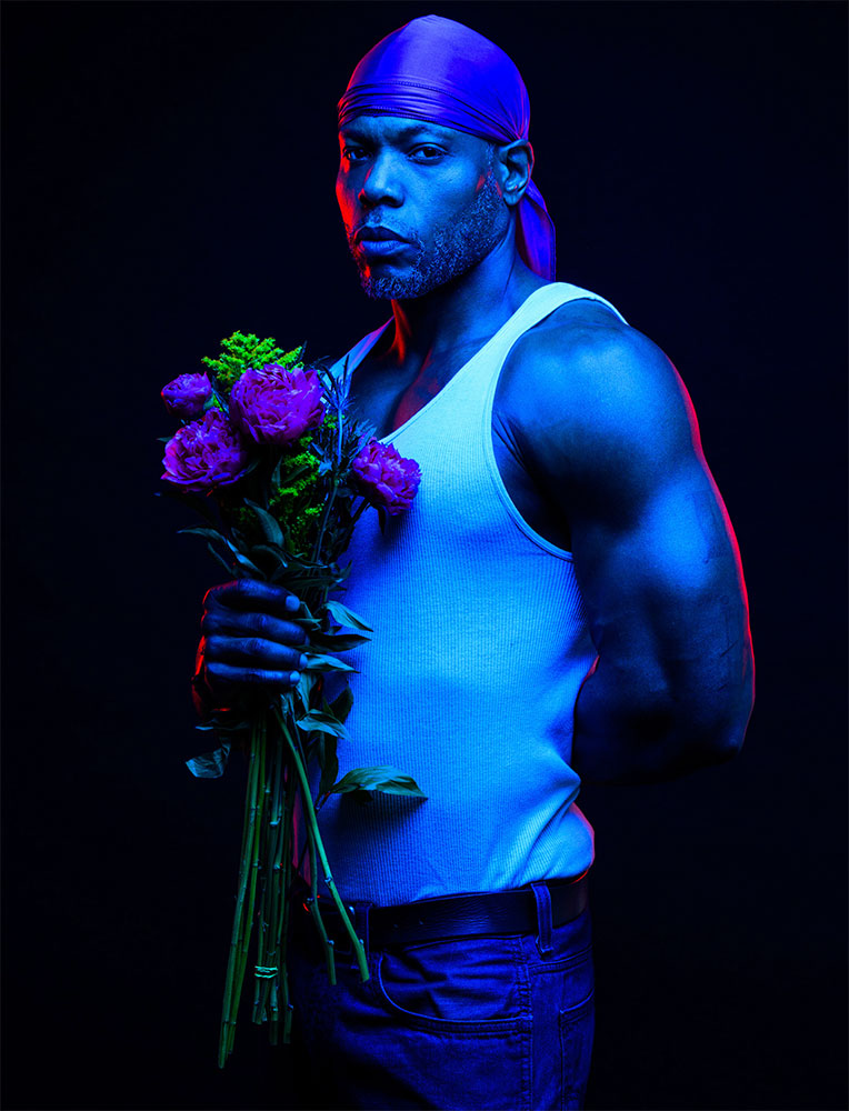 Brett Brown photo of a male model lit with a blue gel and holding flowers