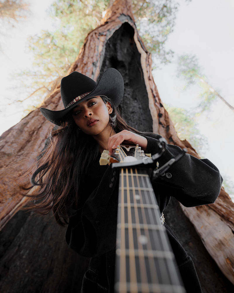 Arturo Carillo photo of a model with a guitar in front of a tree that's burned out from the inside